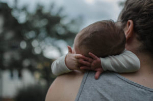 Neugeborenes schläft auf der Schulter seines Vaters im Garten während Baby Fotoshooting Freiburg