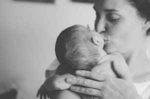 Mutter küsst ihr Neugeborenes während Neugeborenenfotoshooting Freiburg