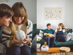 Eine Familie sitzt mit ihrem Neugeborenen auf dem Sofa bei Neugeborenenfotoshooting Zuhause im Wochenbett