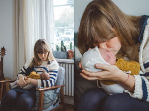 Mutter stillt ihr Neugeborenes Zuhause auf einem Sessel während Neugeborenen Fotoshooting Freiburg