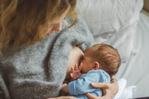 Neugeborenes trinkt an der Brust der Mutter bei Neugeborenen Fotoshooting Freiburg