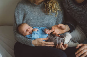 Neugeborenes mit Vater und Mutter im Wochenbett bei Neugeborenenfotoshooting in Freiburg