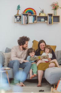 Familie mit zwei Kindern ließt Buch auf dem Sofa bei Familienfotoshooting Freiburg