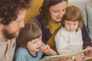 Familie mit zwei Kindern ließt Buch auf dem Sofa bei Familien fotoshooting Freiburg