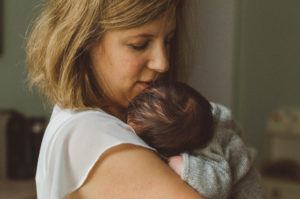 Mutter trägt Baby auf der Schulter bei Neugeboren Fotoshooting Basel