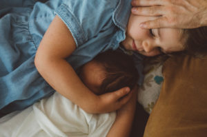 Schwester kuschelt mit Baby bei Neugeboren Fotoshooting Basel