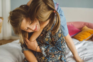 Mutter tobt mit Tochter auf dem Bett bei Familien Fotoshooting Basel