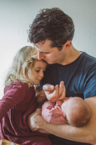 Vater mit Neugeborenen und Tochter bei Neugeborenenfotoshooting in Freiburg