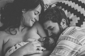 Vater und Mutter mit ihrem Neugeborenen Säugling im Wochenbett entstanden bei Neugeborenenfotoshooting in Freiburg