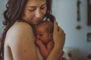 Mutter mit ihrem Neugeborenen Säugling auf dem Arm entstanden bei Neugeborenenfotoshooting in Freiburg