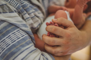 Babyfüße in Papas Händen bei Neugeborenenfotoshooting im Wochenbett Freiburg