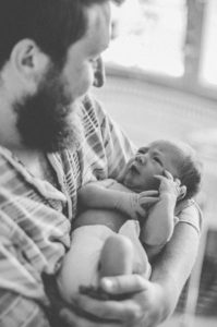 Neugeborenes im Arm seines Vaters bei Babyfotohooting in Freiburg