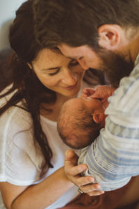 Mutter und Vater betrachten ihr Neugeborenes entstanden bei einem Neugeborenenfotoshooting Freiburg