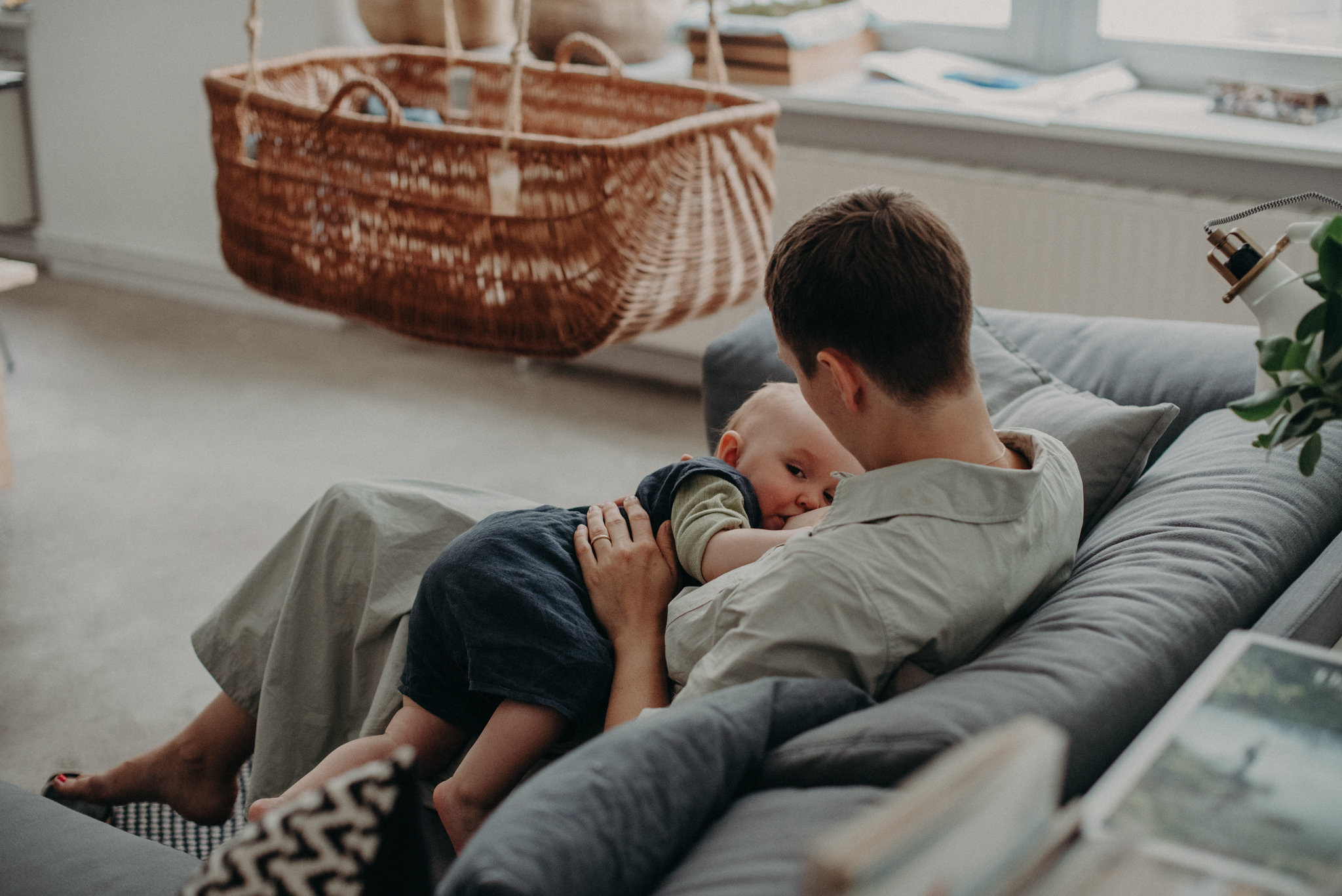 Mutter stillt Kleinkind Zuhause auf der Couch, babyfotograf basel