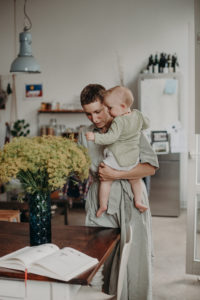 Eine Mutter mit ihrem Baby auf dem Arm betrachten Blumen Foto entstanden bei dokumentarischem Familienfotoshooting in Freiburg