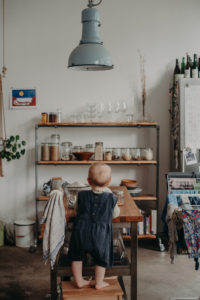 Ein Kleinkind steht auf einem Hocker in Altbauwohnung in der Küche bei Familienshooting in Freiburg
