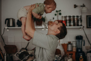 Eine Mutter hebt ihr Baby in die Luft Babyfoto entstanden bei Babyfotoshooting in Freiburg