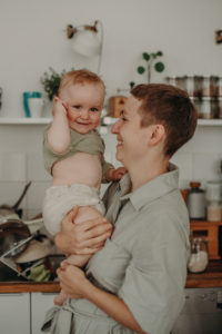 Mutter mit Baby auf dem Arm lachen bei Familienfotoshooting in Freiburg
