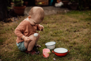 Kleinkind spielt mit Wasser im Garten Foto entstanden bei einem Familienfotoshooting Freiburg
