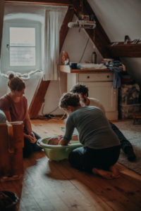 Foto einer Familie mit Neugeborenen im Wochenbett beim ersten Babybad entstanden bei einem Fotoshooting bei Freiburg