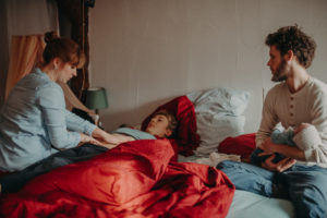 Foto einer Hebamme bei der Nachsorge im Wochenbett entstanden bei einem Familienfotoshooting mit Neugeborenen