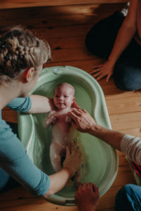 Foto einer Mutter mit Neugeborenen beim ersten Babybad nach der Geburt entstanden bei einem Neugeborenenfotoshooting Zuhause im Wochenbett bei Freiburg