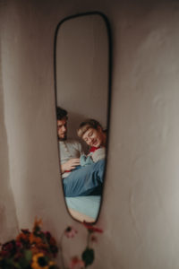 Finalist beim Wettbewerb für dokumentarische Familienfotografie künstlerisches Foto von Spiegelung von einer Familie im Bett mit Neugeborenen im Wochenbett Freiburg