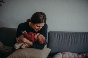 Neugeborenenfoto von liebevoller Mutter mit Baby entstanden bei Babyfotoshooting Zuhause in Freiburg