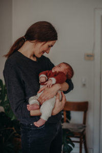 Mutter und Kind natürliches Familienfoto mit Neugeborenem entstanden bei Babyfotoshooting Zuhause in Freiburg