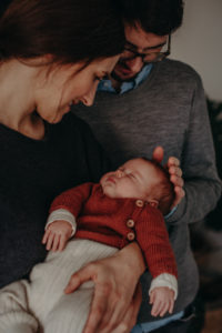 Familienfoto Neugeborenenfoto von schlafendem Baby auf dem Arm der Eltern entstanden bei Babyfotoshooting Zuhause in Freiburg