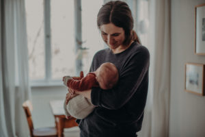 Natürliches Neugeborenenfoto von schlafendem Baby entstanden im Arm der Mutter bei Babyfotoshooting Zuhause in Freiburg