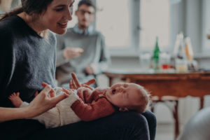 Natürliches Neugeborenenfoto von gähnendem Baby im Arm der Mutter bei Babyfotoshooting Zuhause in Freiburg