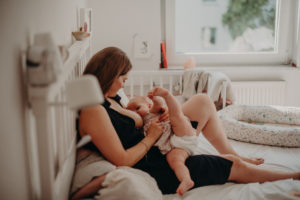 Mutter stillt Kind im Bett, natürliches Familienfoto entstanden bei Familienfotoshooting in Freiburg