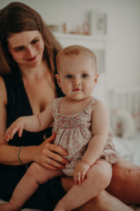 Mutter mit Baby auf dem Schoß, natürliches Familienfoto entstanden bei Familienfotoshooting in Freiburg