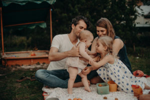Familie auf Picknickdecke im Garten, natürliches Familienfoto entstanden bei Familienfotoshooting in Freiburg