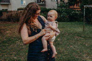 Babyfoto von Baby mit Mutter im Hinterhof, natürliches Familienfoto entstanden bei Familienfotoshooting in Freiburg