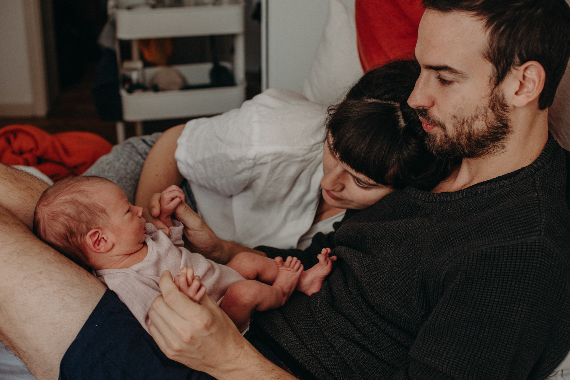 Eltern betrachten ihr Neugeborenes Baby im Wochenbett, Fotograf in Basel