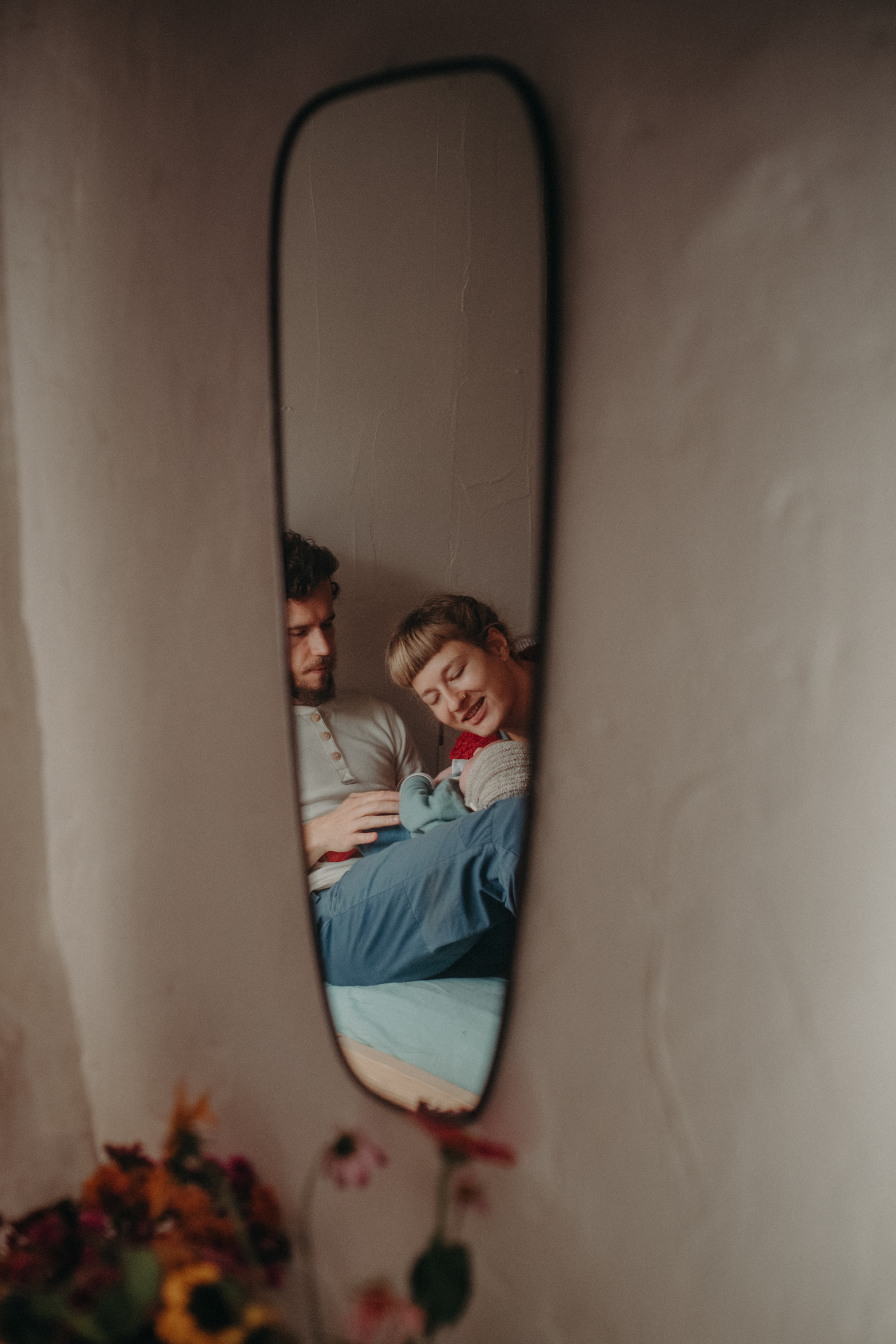 Finalist beim Wettbewerb für dokumentarische Familienfotografie künstlerisches Foto von Spiegelung von einer Familie im Bett mit Neugeborenen im Wochenbett Freiburg