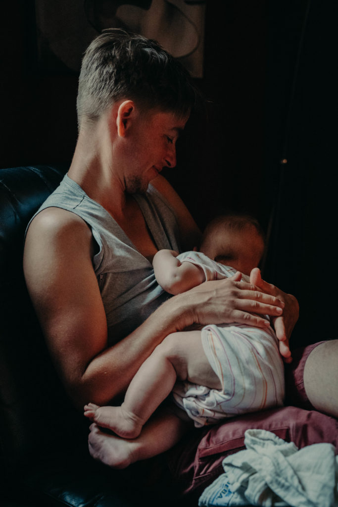 Stockfotos lgbtqia+ ein Trans Vater stillt lächelnd sein Baby
