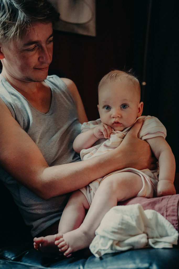 Stockfotos lgbtqia+ ein Trans Vater hält sein Baby, das in die Kamera schaut